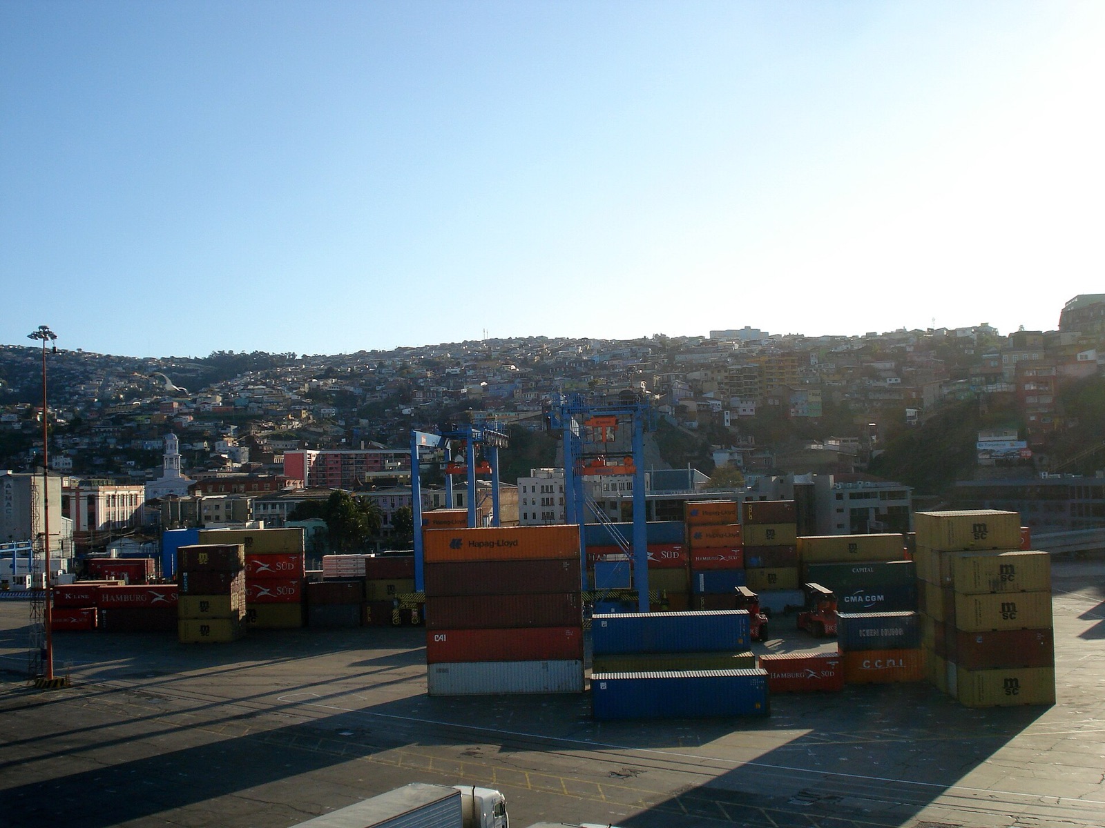 Terminal de contenedores del puerto de Valparaíso a nivel de suelo, con grúas pórtico y los cerros de la ciudad al fondo